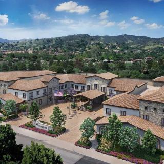 Aerial view of a residential building complex surrounded by lush greenery and hills.
