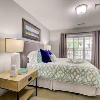 A cozy bedroom featuring a neatly made bed with patterned bedding, two nightstands, and a large window with curtains.