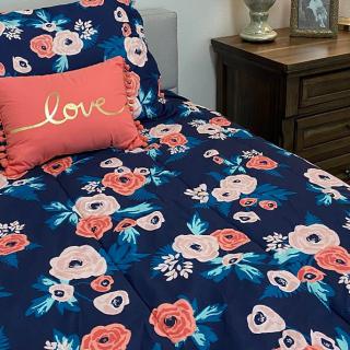 A cozy bedroom setup featuring floral-patterned bedding and a 'love' accent pillow.