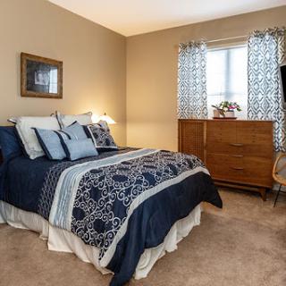 A cozy and well-decorated bedroom featuring a comfortable bed, stylish curtains, and a wooden dresser.