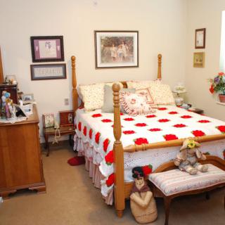 A cozy bedroom with vintage decor and a colorful quilted bedspread.