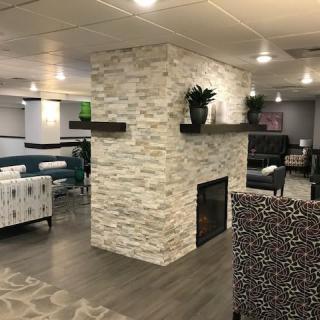 A modern lounge area featuring a central stone fireplace surrounded by contemporary furniture.