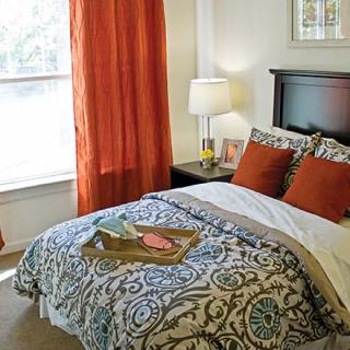 A cozy bedroom with orange accents and a stylish bedding set.