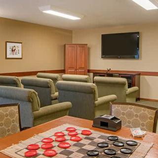 A cozy recreation room featuring a checkers board, comfortable seating, and a television.