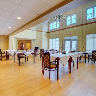A spacious dining area with neatly arranged tables and chairs, illuminated by natural light.