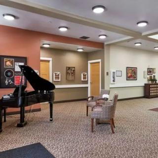 A cozy lobby area featuring a grand piano and comfortable seating, adorned with artwork on the walls.