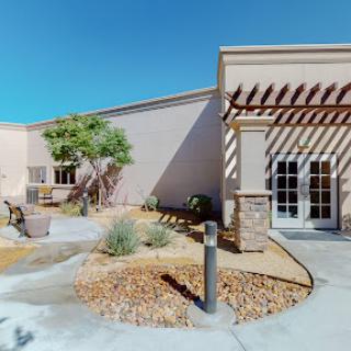 A modern building with contemporary architecture surrounded by desert landscaping under a clear blue sky.