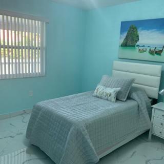 A cozy bedroom with turquoise walls, featuring a single bed and minimalist decor.