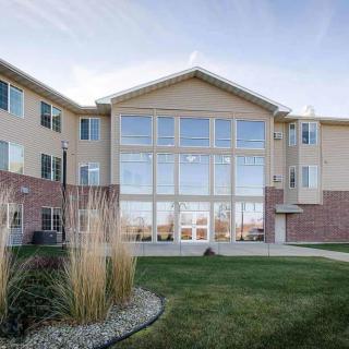 A modern residential building with large windows and a well-maintained lawn.