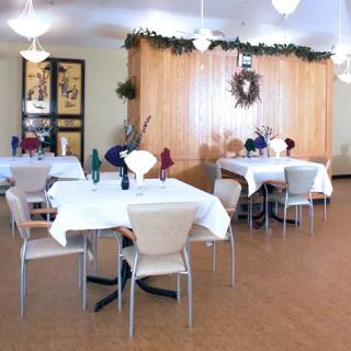 A festive dining area with decorated tables and holiday wreath on the wall.