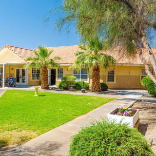 A suburban house with a lush lawn and palm trees under a clear blue sky.