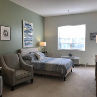 A cozy, well-decorated bedroom with a large bed, comfortable chairs, and soft lighting.