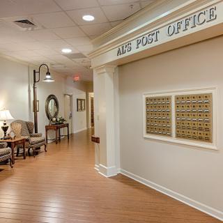 A hallway with a traditional post office setup, featuring a seating area and mailboxes.