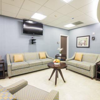 A modern waiting room with comfortable sofas and a television.
