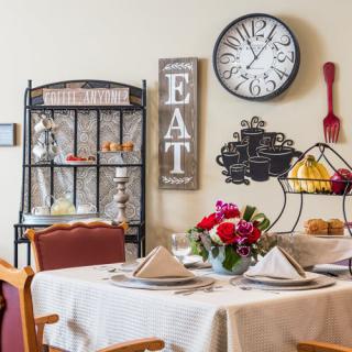 A cozy dining area with a neatly set table, adorned with flowers and surrounded by charming wall decor.