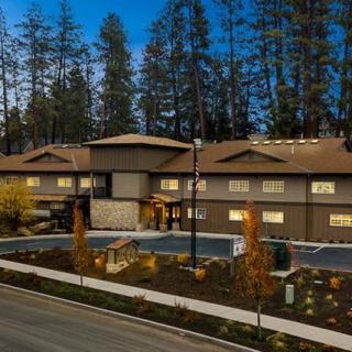 A modern residential building surrounded by trees, captured in the evening.