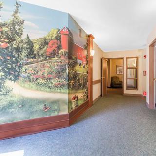 A hallway featuring a colorful mural depicting a scenic nature view with trees and a red barn.
