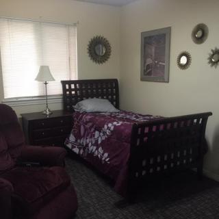 A cozy bedroom with a single bed, armchair, and decorative items on the wall.