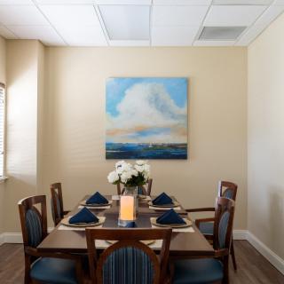 A neatly set dining room table with a floral centerpiece and artwork on the wall.