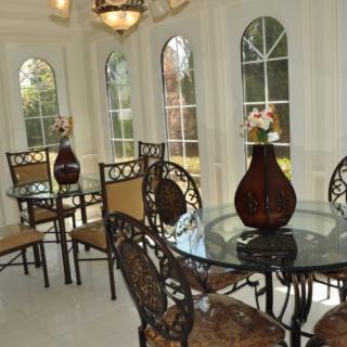 A bright dining area featuring glass tables, ornate chairs, and large windows allowing natural light to flood the space.