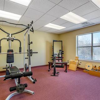 A small gym room with various fitness equipment including a weight machine and free weights.