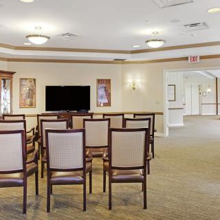 A well-lit conference room with rows of chairs facing a television.