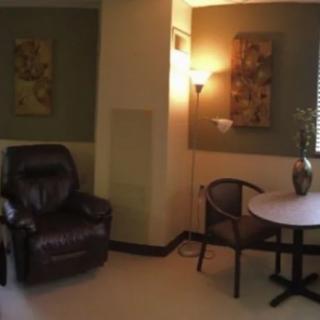 A cozy living room corner with a leather recliner, round table, and decorative lamp.