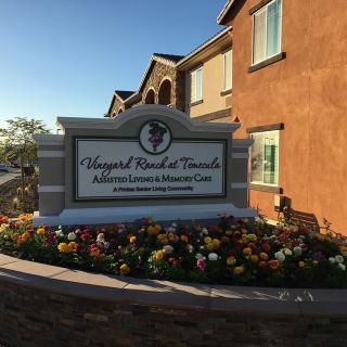 A residential sign in front of a building surrounded by colorful flowers.