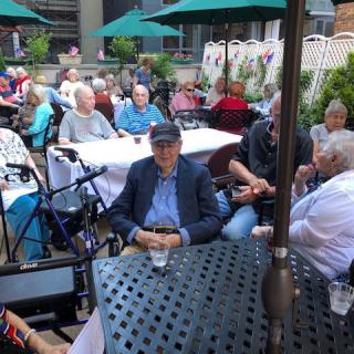 A group of people enjoying an outdoor gathering on a patio with tables and umbrellas.