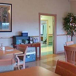 A cozy dining area with tables and chairs, featuring a plant decoration and artwork on the wall.
