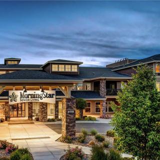 A well-lit building entrance at dusk with a landscaped front.