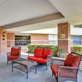 A cozy outdoor patio area with red cushioned wicker furniture under a covered space.