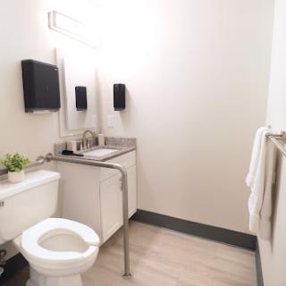 A modern and minimalist bathroom featuring a sink, toilet, and mirrors.
