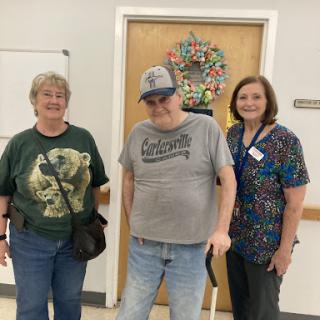 A cheerful moment shared between an elderly man and two women in a healthcare setting.