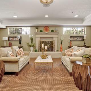 A cozy and elegantly decorated living room featuring two sofas, a coffee table, and a central fireplace.