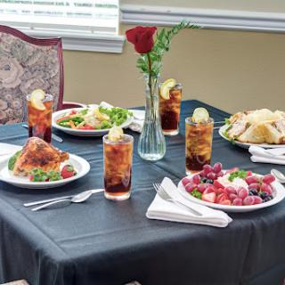 A beautifully arranged table featuring a delicious meal, complete with drinks and fresh flowers.