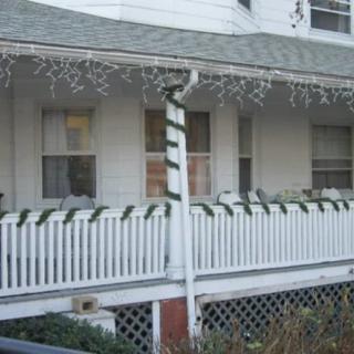 A house porch decorated with holiday lights and garlands.