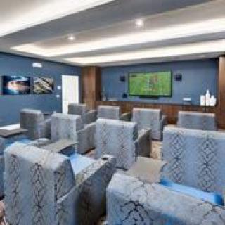 A modern home theater with rows of comfortable seating and a large screen on the wall.