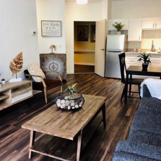 A modern and cozy living room with a connected kitchen and dining area, featuring wooden furniture and stylish decor.