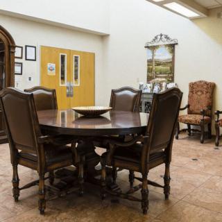 A dining area with a round wooden table surrounded by chairs, featuring elegant decor and a warm atmosphere.