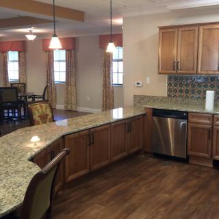 A spacious kitchen with granite countertops and wooden cabinets opens into a dining area.