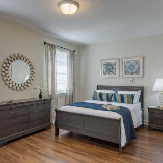 A cozy bedroom with a stylish bed, matching dresser, and elegant decor.