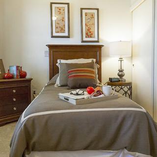 A cozy bedroom with a single bed, featuring stylish decor and a tray of breakfast on the bed.