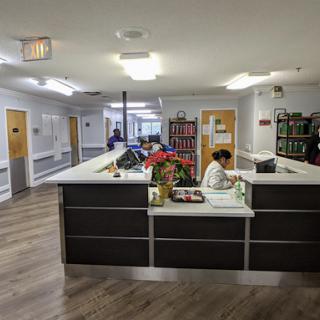 A view of the reception area in a healthcare facility, featuring a desk and staff attending to visitors.
