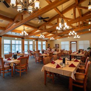 Elegant restaurant interior with wooden beams and chandeliers.