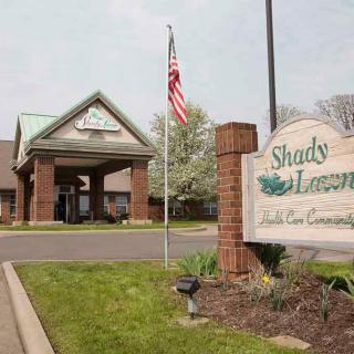 Entrance to Shady Lawn, featuring an American flag and landscaped surroundings.