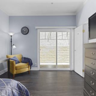 A modern bedroom featuring a yellow armchair, hardwood floors, and large sliding doors that let in natural light.