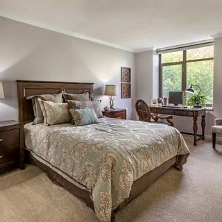 A cozy bedroom with elegant decor, featuring a comfortable bed and a work desk by the window.