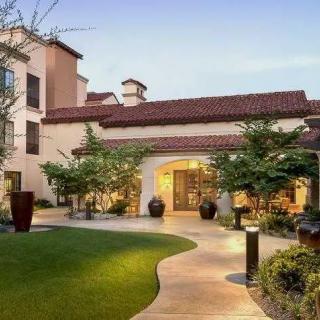 A beautifully landscaped entrance to a modern building with a paved walkway and greenery.