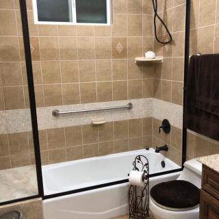 A modern bathroom with a tiled shower and bathtub area, featuring a glass door and mounted towel rack.